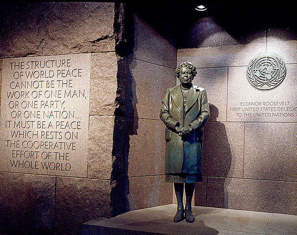 estatua de bronce frente al logo de las naciones unidas
