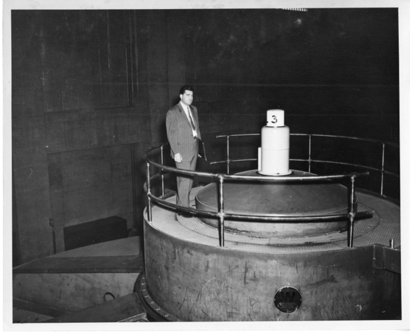 J.B. Hamlin, visiting mechanical engineer, stands atop dam generator