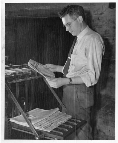 Bill Wilmot, Editor of Pasco Herald, examines a copy of newspaper fresh off press