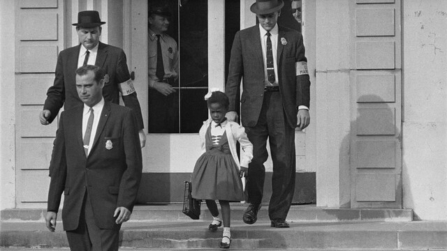 Ruby Bridges is escorted to school by armed officials.
