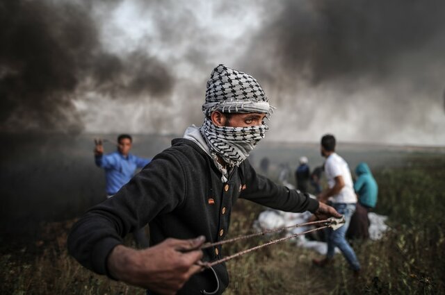 A Palestinian protester uses a slingshot to throw stones toward Israeli forc