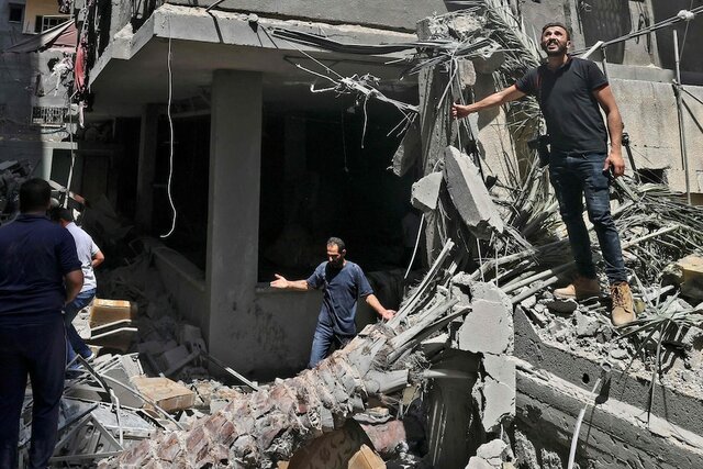 Palestinians inspect buildings damaged during Israeli airstrikes in Gaza City.