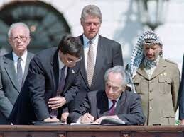 Israeli Foreign Minister Shimon Peres, center, signs the first of the Oslo accords
