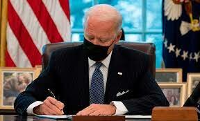 (L) President Joe Biden signs an executive order repealing the 2019 Trump-era ban on most transgender Americans joining the military.