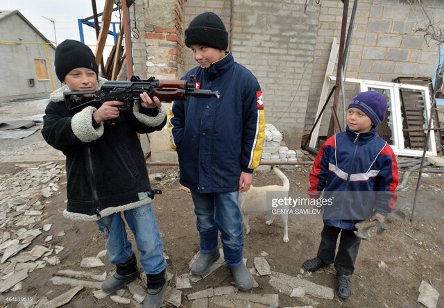 Ragazzi giocano con un fucile mitragliatore scarico che è stato dato loro dai militari ucraini