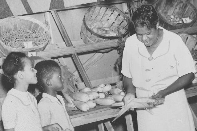 Nannie Helen Burroughs and children at farm stand conneced with her training school for women and girls. Afro American Newspaper