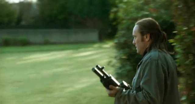 a man accompanied by others already seen with a gun approaching a house