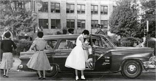 A mob gathers around in front of the school, the nine black students go inside through a side door. A white student takes them to the principal's office where they are to receive their class assignments. When the mob learns the students are inside, it bec
