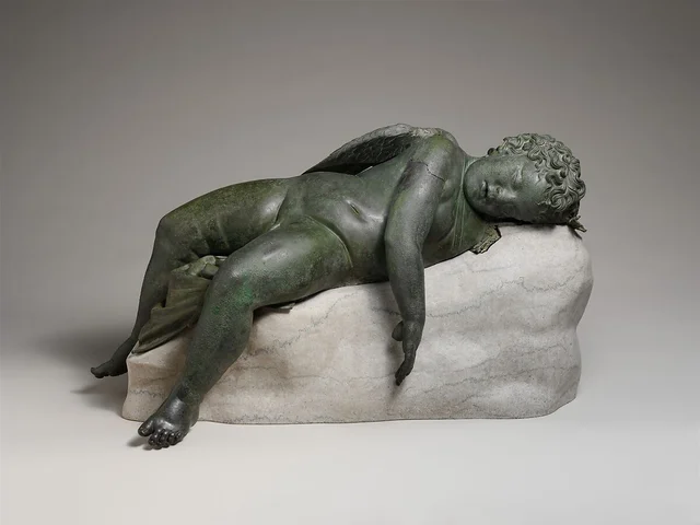 Bronze statue of Eros sleeping, 3rd–2nd century B.C.E., bronze, 16 1/2 × 14 × 33 9/16″ / 41.9 × 35.6 × 85.2 cm (The Metropolitan Museum of Art).