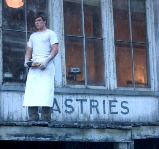 Peeta helps Katniss when he throws her the bread