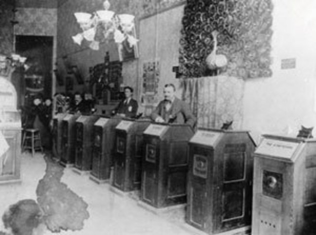 Coin-operated Kinetoscopes appear in a New York City amusement arcade.