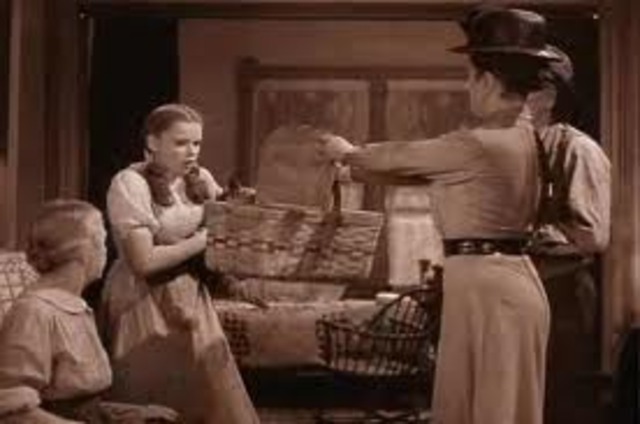 Almira Gulch comes with a "warrant" for taking Toto to the sheriff.