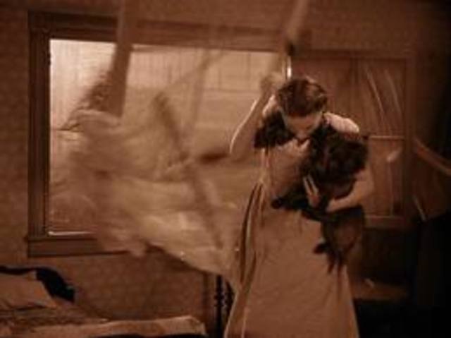 Dorothy gets hit in the head with a window that's blown in.