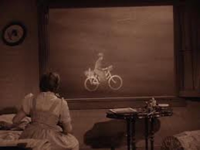 Dorothy wakes up and the house is spinning. The wicked witch appears on a broom in the window.