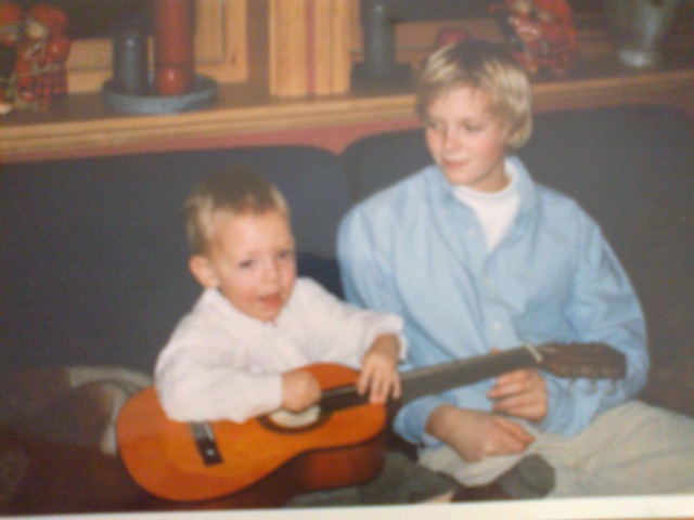 Thomas is playing his mini-sized gitar infront of Jostein (Second oldest brother) in Norway, Hønefoss