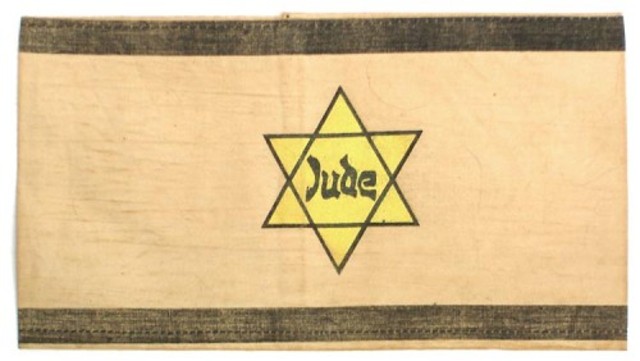 Germans force Jews in Poland to wear a yellow Star of David on their chests or a blue-and-white Star of David armband.
