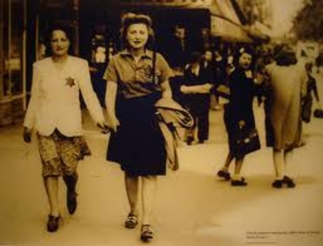 Germans force Jews in Poland to wear a yellow Star of David on their chests or a blue-and-white Star of David armband.