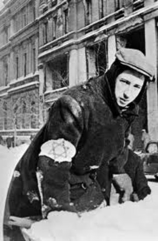 Germans force Jews in Poland to wear a yellow Star of David on their chests or a blue-and-white Star of David armband.