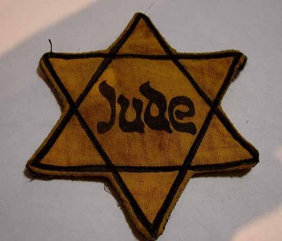 Germans force Jews in Poland to wear a yellow Star of David on their chests or a blue-and-white Star of David armband.