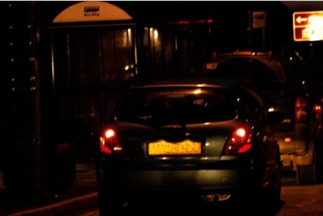 Ein Auto ohne Licht kommt und Hubner fotografiert.