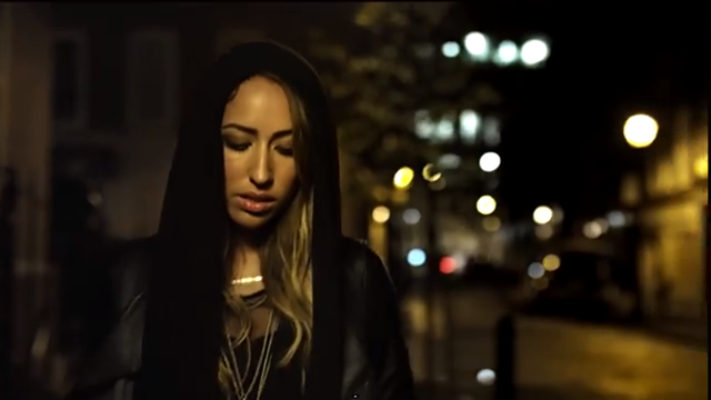 The first shot shows lighting that flatters the artist, playing close attention to her make-up (part of costume). We also get and idea of her city setting