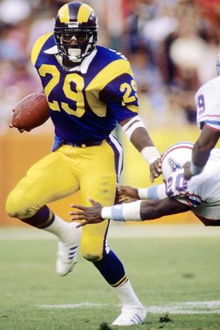 Eric Dickerson of the Los Angeles Rams gains 215 yards rushing against the Houston Oilers to pass O.J. Simpson`s single-season NFL rushing record of 2,003 yards. Dickerson finished the season with 2,105 yards rushing.