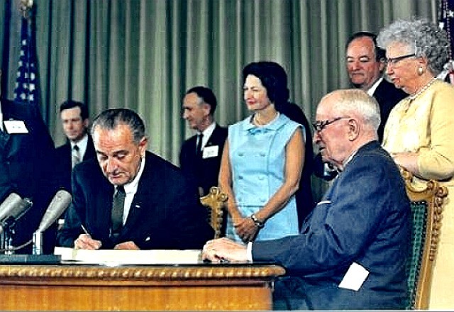 President Lyndon Johnson signs Medicare and Medicaid into law.