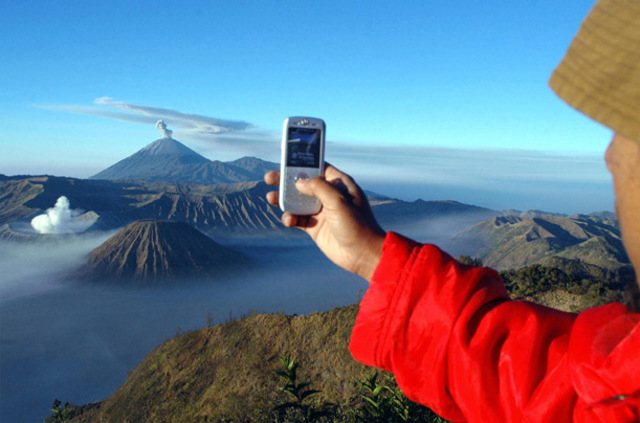 A tourist uses his phone to photograph volcanoes in Indonesia.