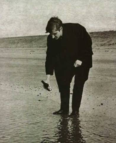 Wim T. Schippers giet een flesje frisdrank leeg in de zee bij Petten