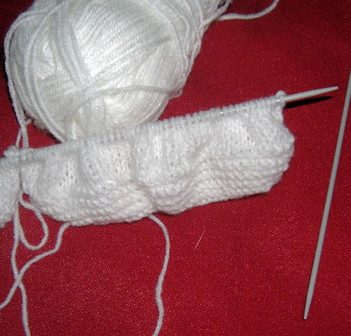 Tejido sin terminar. Tejido de lana a dos agujas.