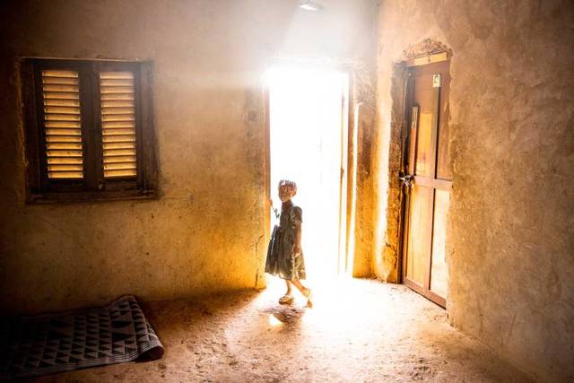 A young girls stands in the doorway of a house, two days after a member of her family was killed by a grenade said to be launched by a member of Séléka. Bangui, Central African Republic. Photo by William Daniels.