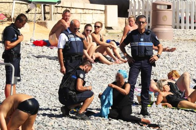 Photo de policiers niçois verbalisant une femme portant un voile sur la plage de Nice
