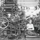 Women and child in mill behind machine 11