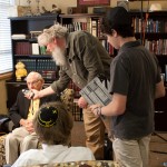 Photo of filmmaker Jacob Rhodes checks the lighting as Grady High School students Eli Mansbach (standing) and Jack Arnold prepare to interview Holocaust survivor Herbert Kohn as part of the Congregation Shearith Israel Teen Film Project.