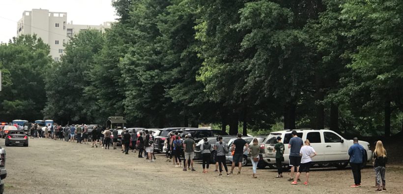 Dozens and dozens of people in a line in a parking lot