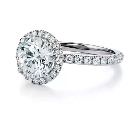 Elegant platinum engagement ring with a dazzling round-cut diamond center stone and a halo of small diamonds along the band, displayed on a clean white background.