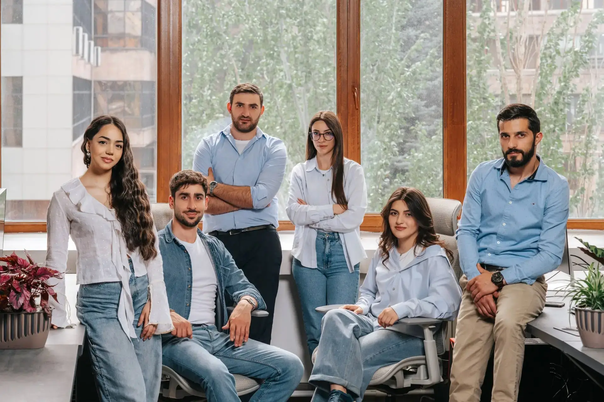 A team of six casually dressed people pose for a professional group photo.