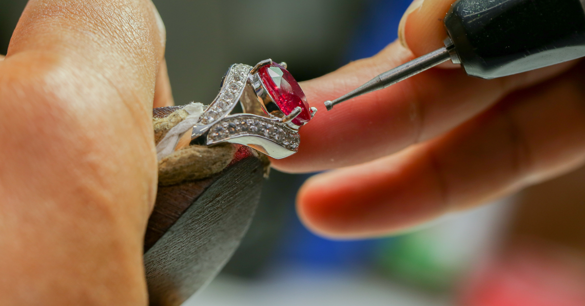 Jeweler working on a ring with red gemstone
