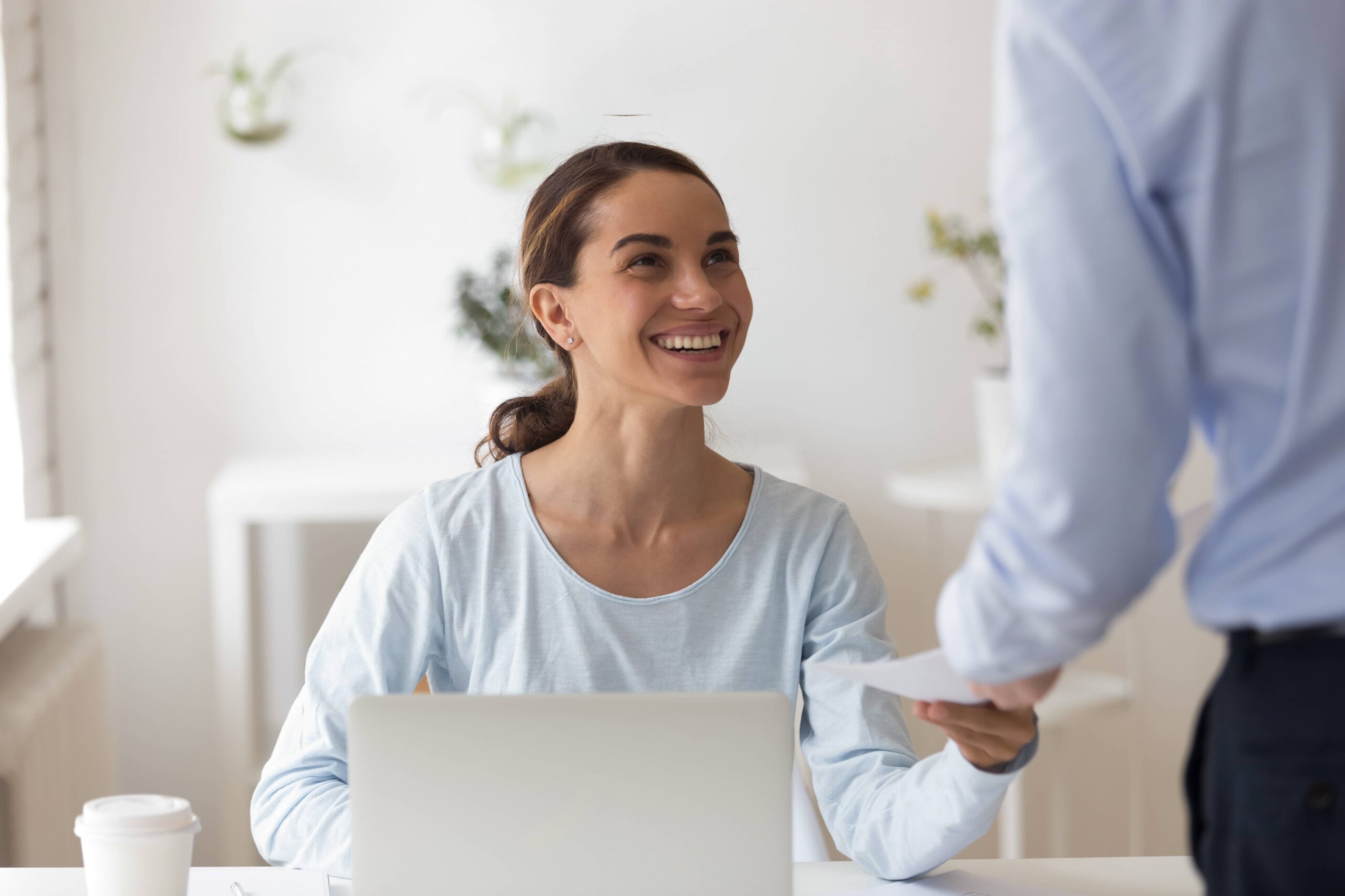 Small business employer giving female employee a piece of paper