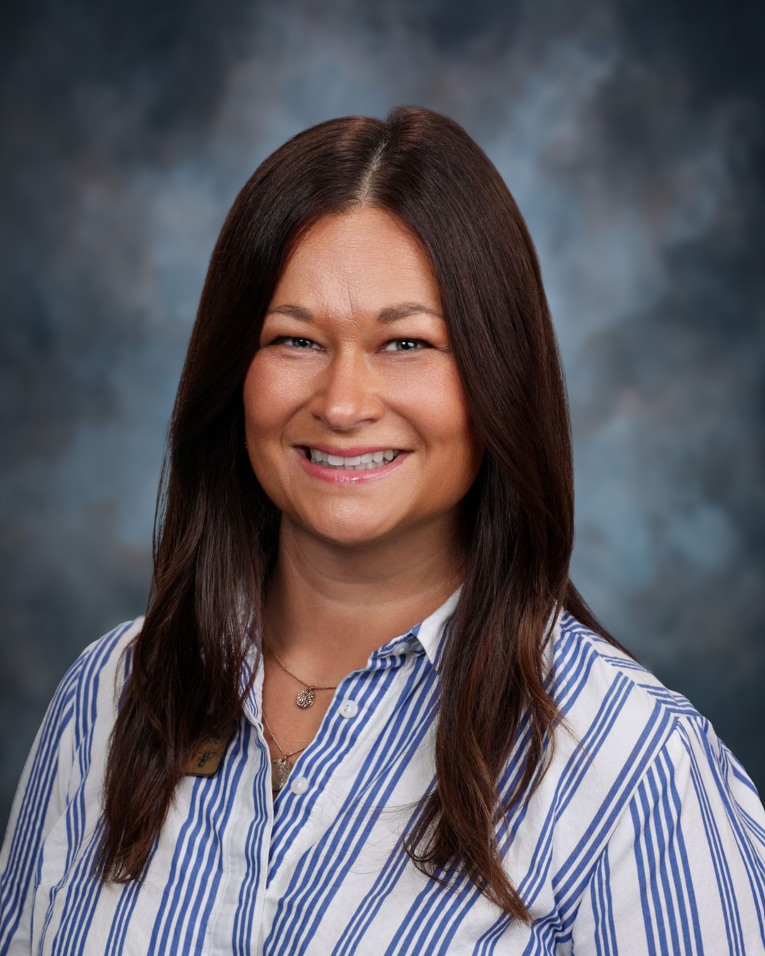 A woman with long brown hair smiles at the camera.