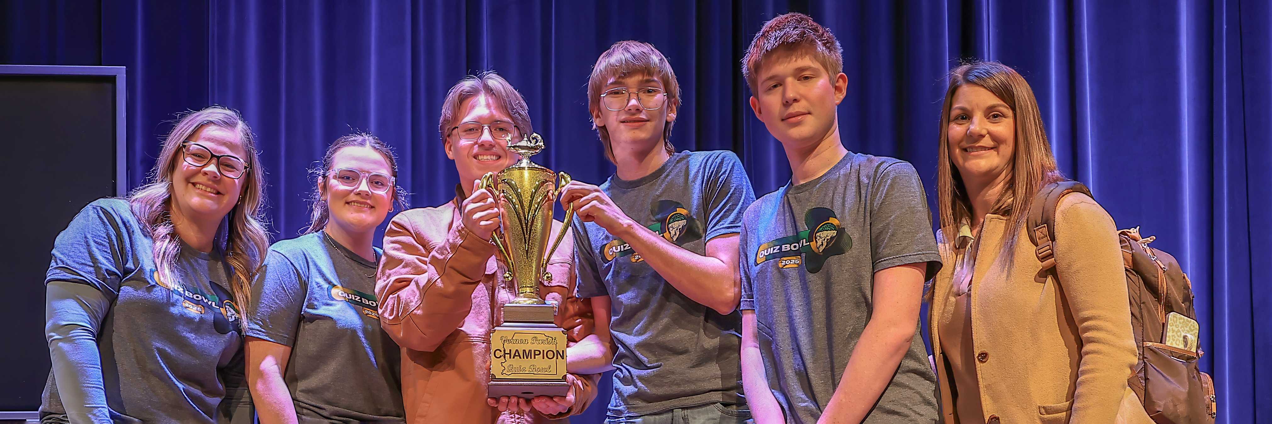 A group of young people smile and pose for a photo on a stage.