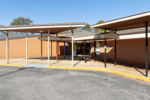 Covered walkways lead to a building with a brick facade.