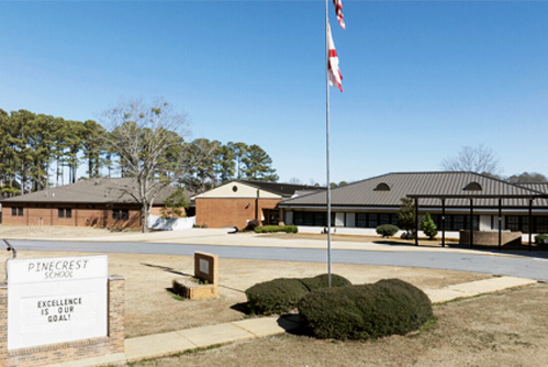 A low-rise brick building with a flag pole on a sunny day.
