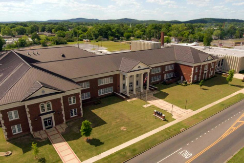 An aerial view of a large brick building with a brown roof and white columns.