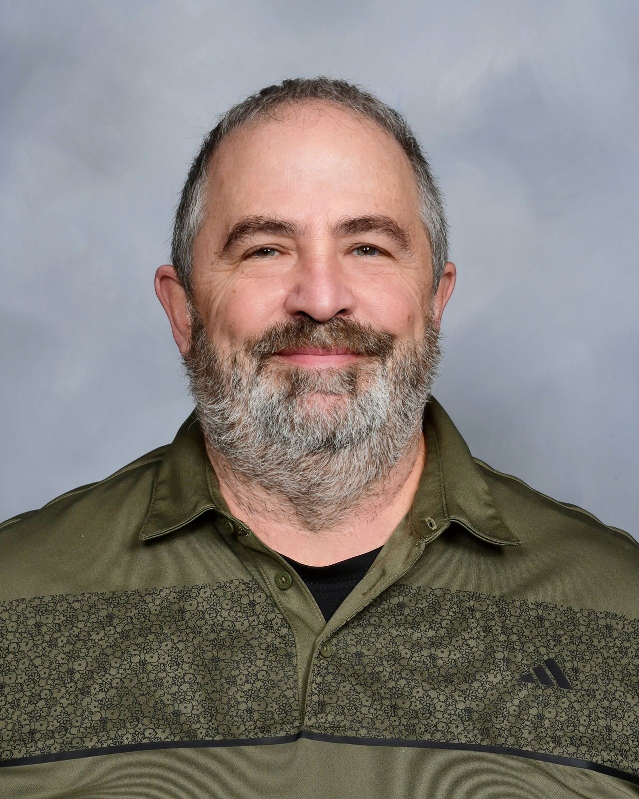 A man with a beard and mustache smiles at the camera.
