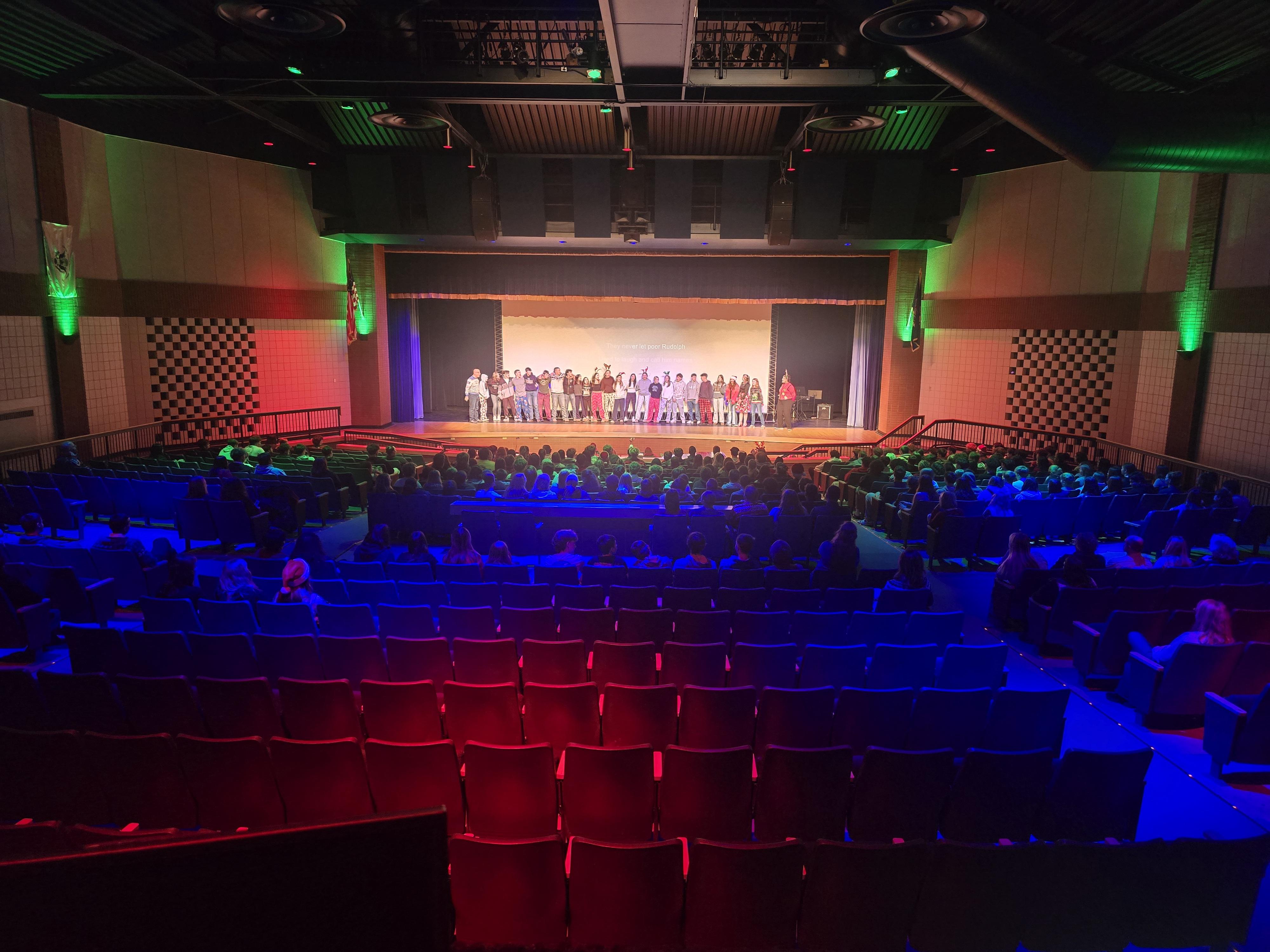 HS auditorium is lit with colorful stage lights, ready for a performance.