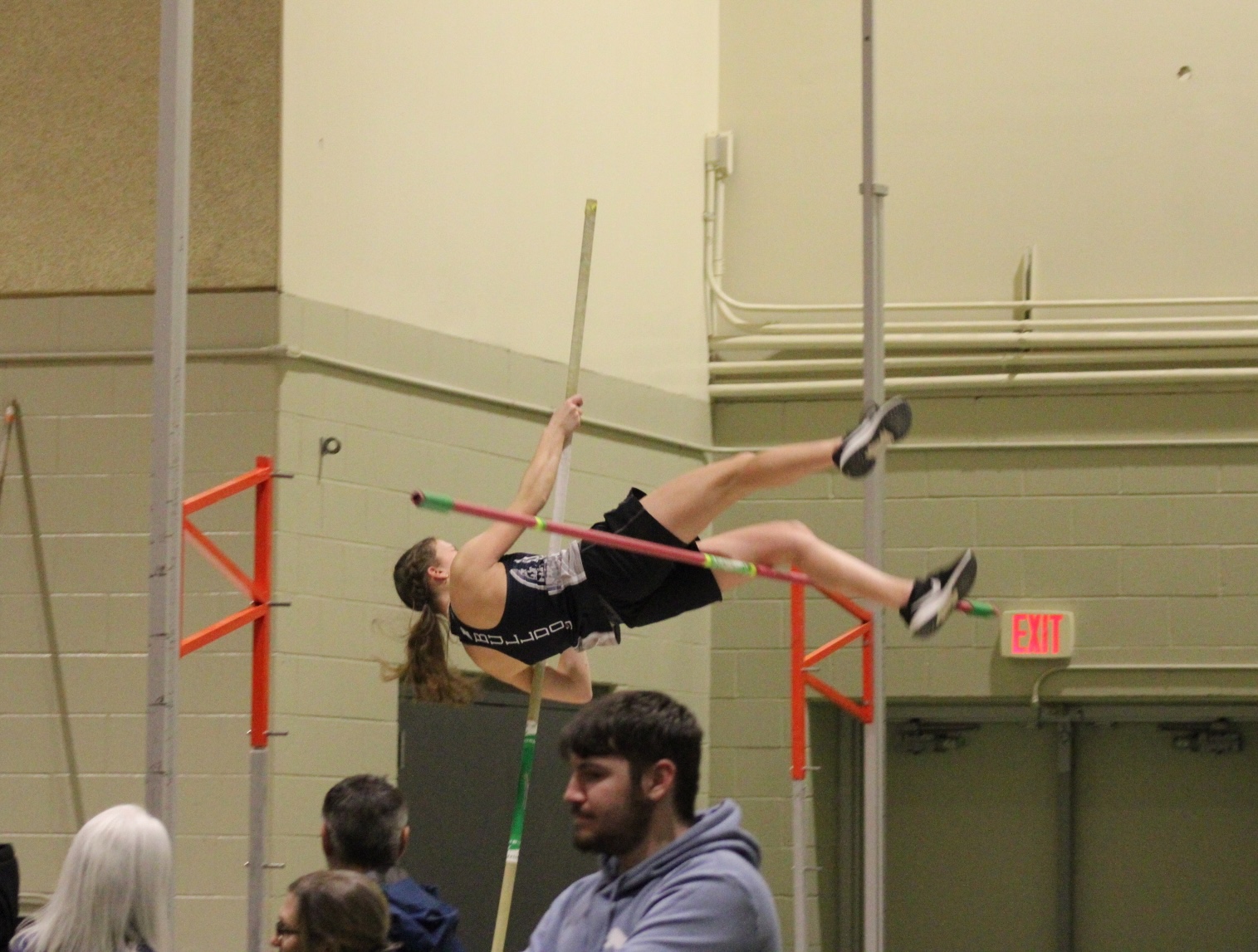 A pole vaulter clears the bar during an indoor competition.