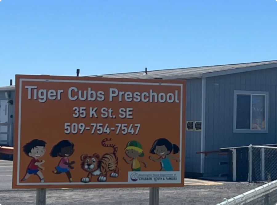 A sign for Tiger Cub Preschool displays colorful illustrations of children and a tiger.