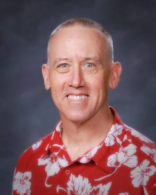 A photo of Jay Mills, Counselor wearing a red Hawaiian shirt with white floral patterns.