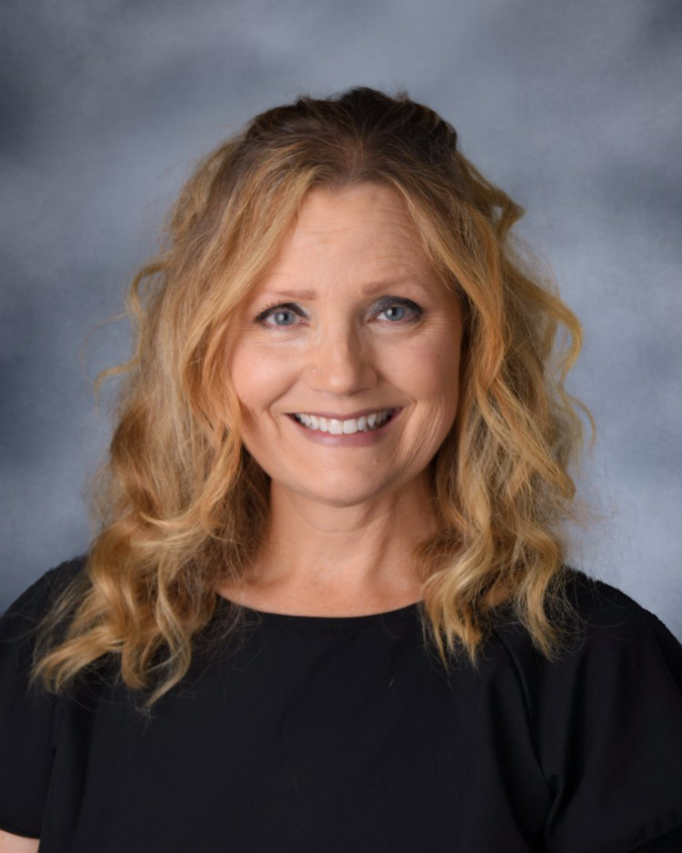 A woman with blonde, wavy hair smiles at the camera.